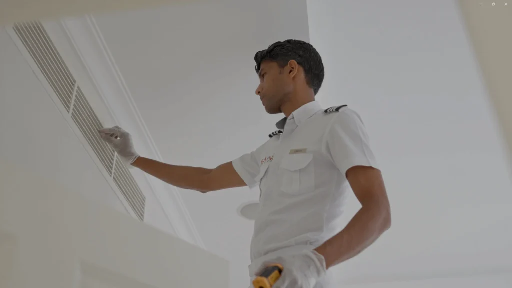 Guy wearing white inspecting a Air conditioner