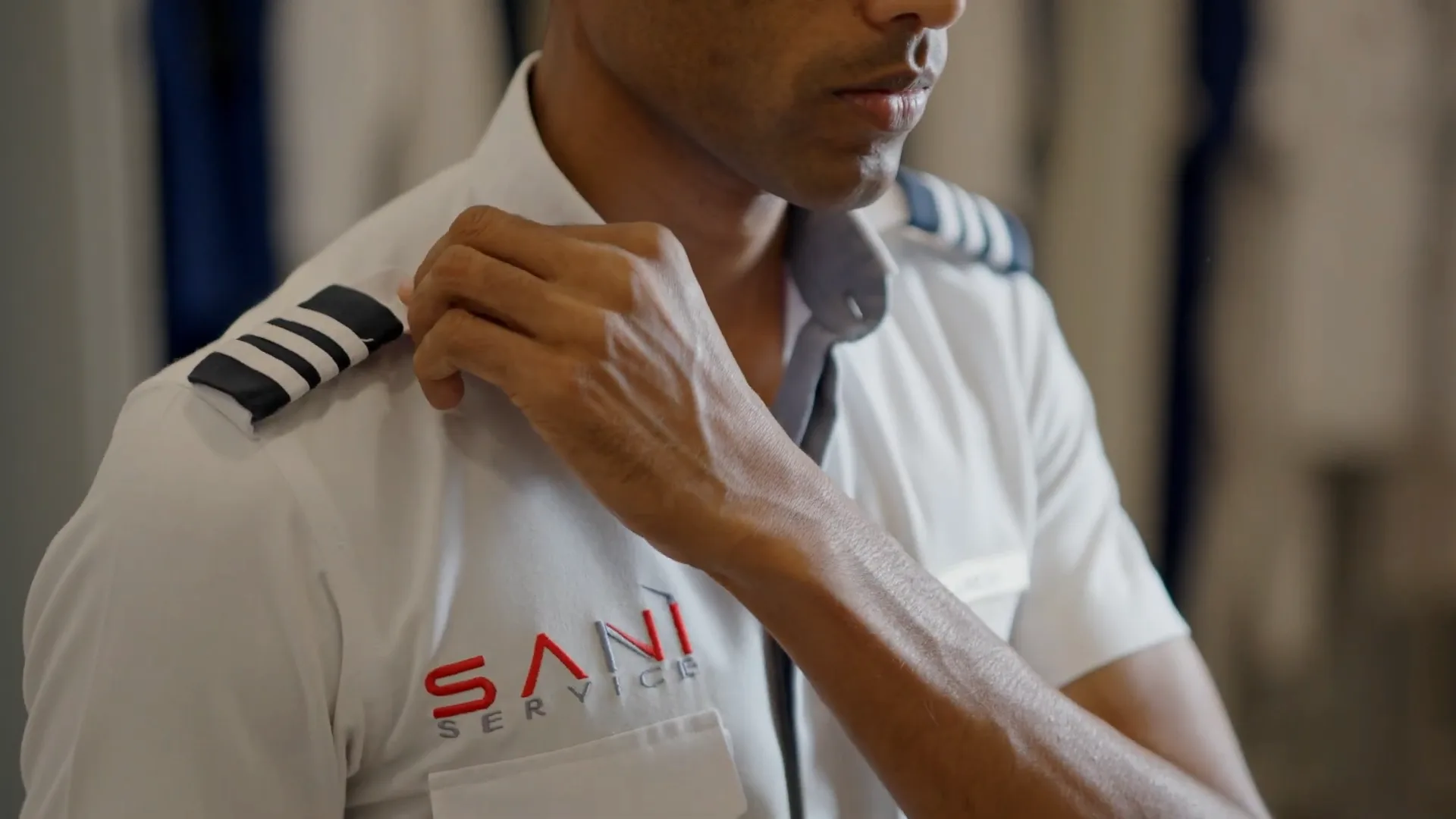 A Saniservice technician in pilot-style uniform with captain's epaulettes