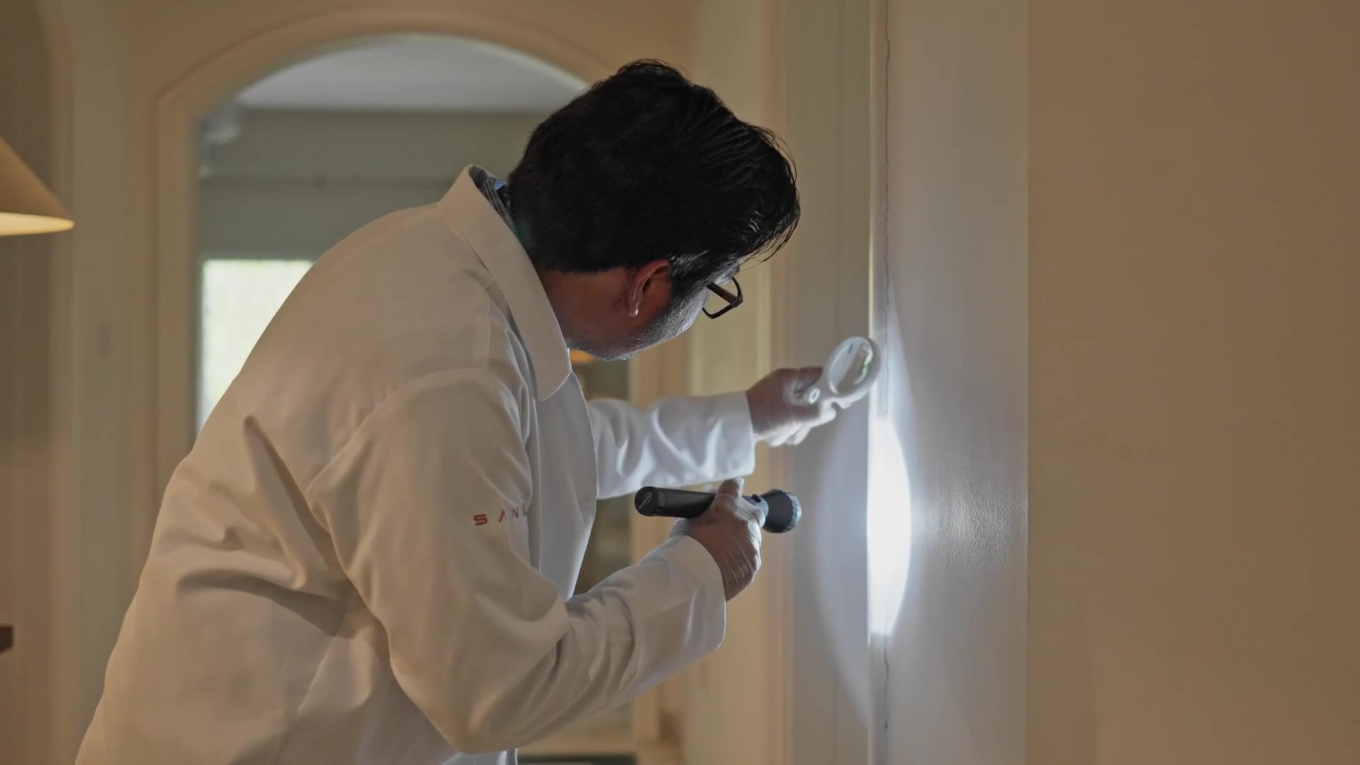 Interior termite inspection of villa joinery, examining timber with a magnifier and torch